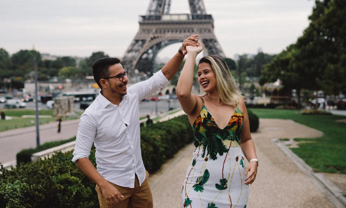 Joyful couple celebrating in front of Eiffel Tower Paris, candid engagement photography, summer session