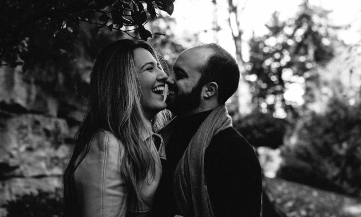 Black and white candid portrait of laughing couple, intimate Paris engagement session in nature