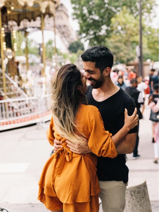 Couple embracing near vintage carousel at Eiffel Tower, golden hour Paris engagement photography