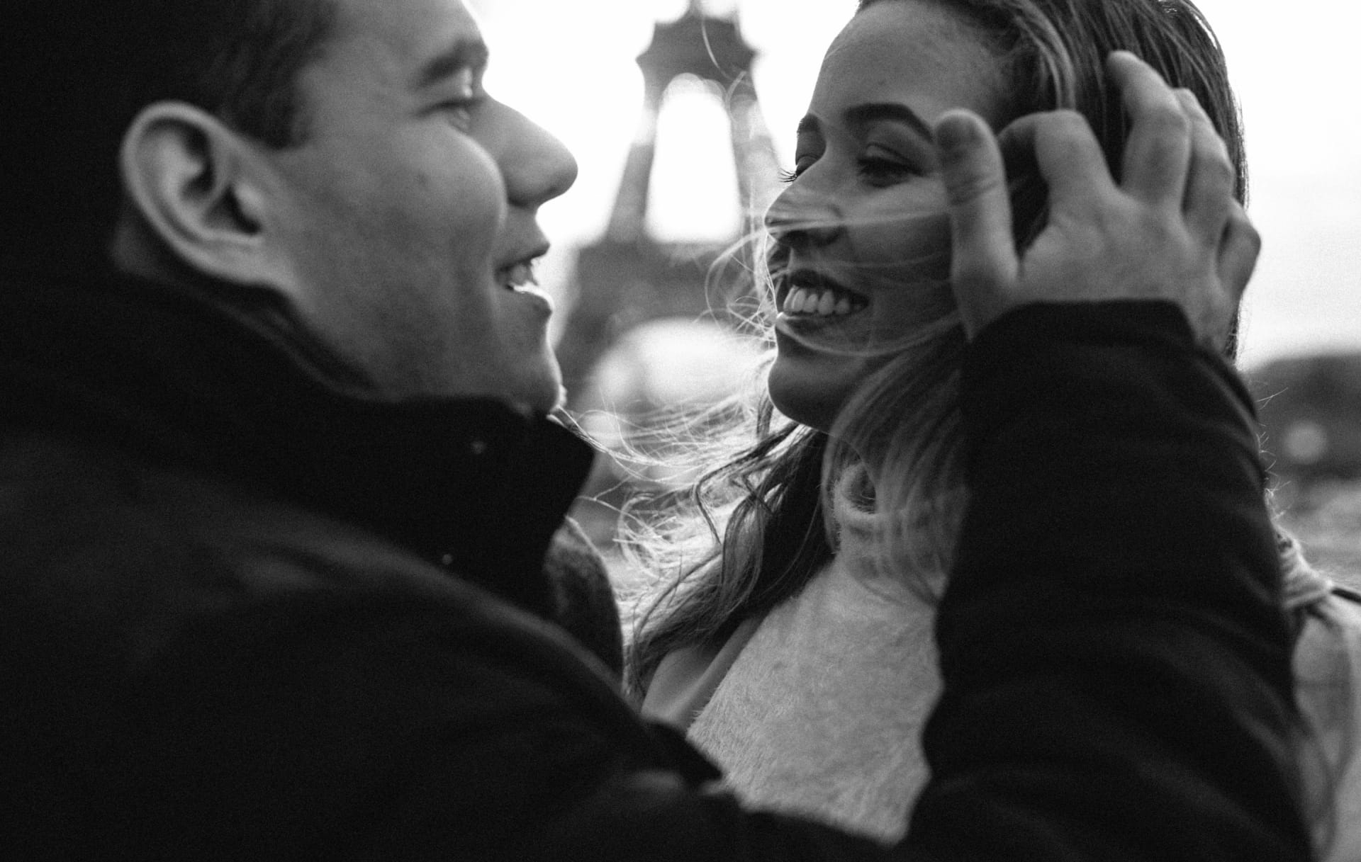 Couple photo in Paris, a man tucking his wife's hair behind her ear near the Eiffel Tower 1