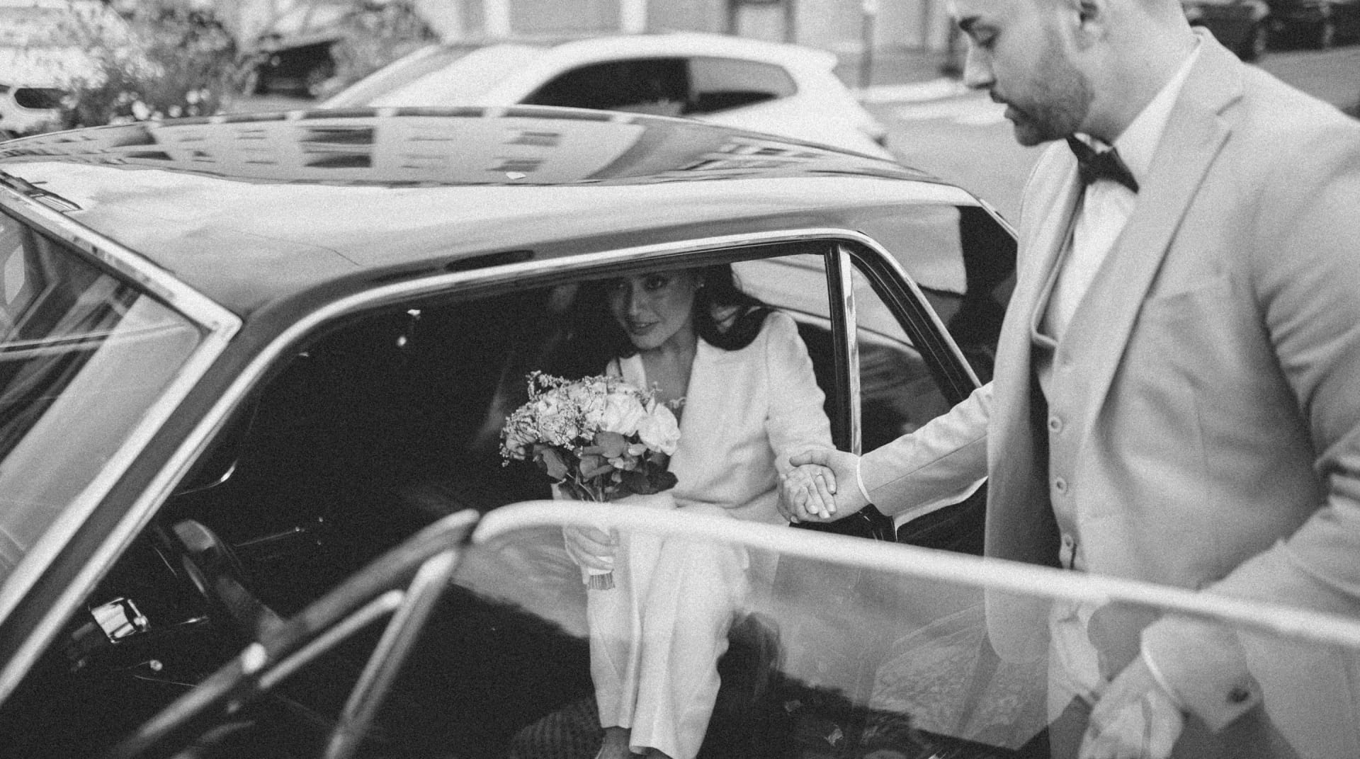 Wedding photo in Paris of a bride holding getting out of his wedding card with the help of the husband 1