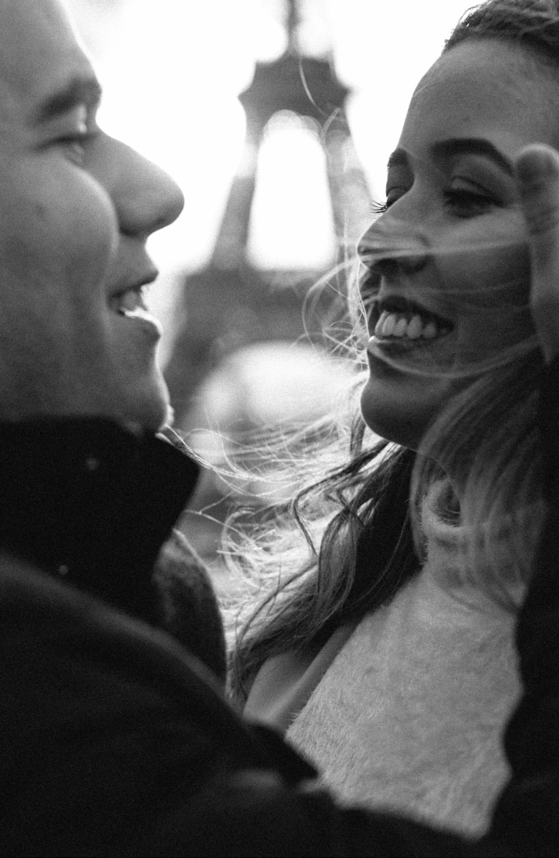 Couple photo in Paris, a man tucking his wife's hair behind her ear near the Eiffel Tower 1
