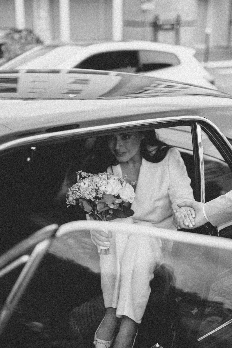 Wedding photo in Paris of a bride holding getting out of his wedding card with the help of the husband 1